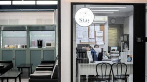 A modern interior with a reception desk, seating area, and kitchen visible through glass doors. - Stay Wanglang (Bangkok)
