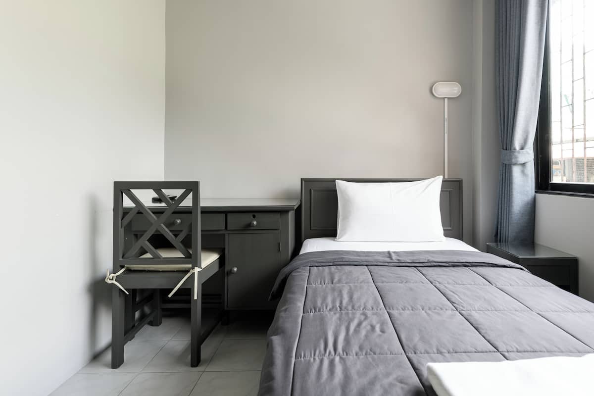 A neatly arranged bedroom with a bed, a desk, and a chair.