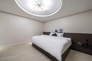 A modern bedroom with a large bed, a circular ceiling light, and a nightstand with a lamp. - Hotel KNOX (Cheonan)