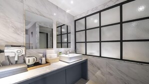 Un bagno moderno con un mobile lavabo in marmo, uno specchio grande e una finestra con vetro satinato.