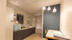 Un bagno moderno con un vanità in marmo, un lavandino e uno specchio. È presente un tavolino con una sedia e un asciugamano.