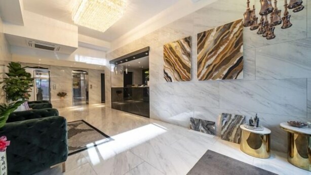 Una hall moderna con pareti in marmo, un lampadario e una reception.