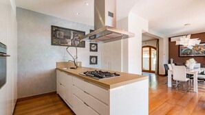 Une cuisine moderne dotée d’un îlot central, de meubles blancs et d’une hotte en acier inoxydable.