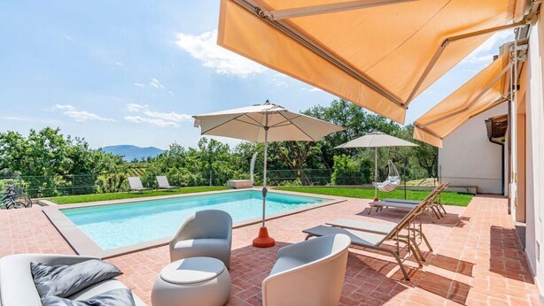 Un espace aménagé au bord de la piscine, avec des chaises longues, une table et des parasols.