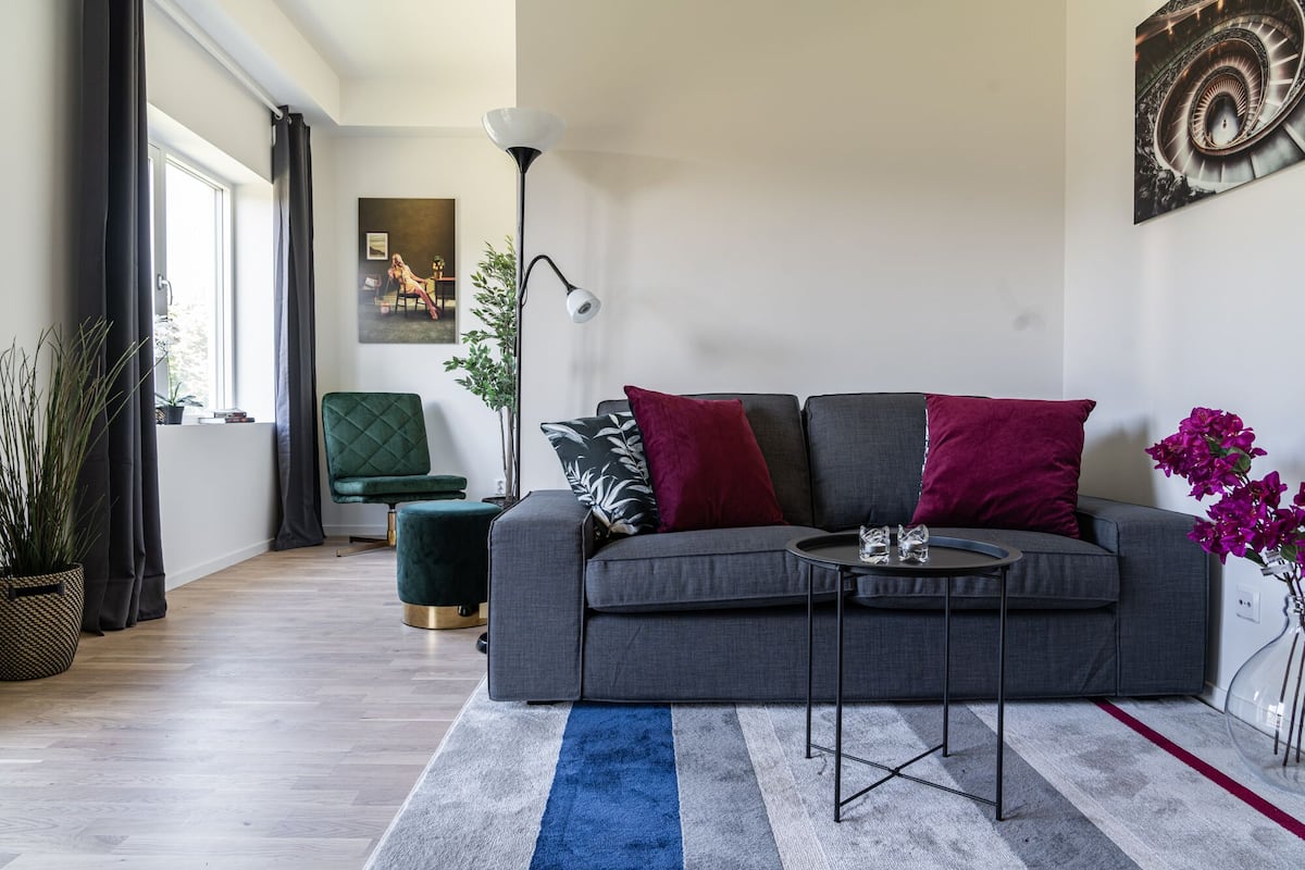 Una sala de estar moderna con un sofá gris, una mesa de centro redonda y un tapete azul y blanco a rayas.