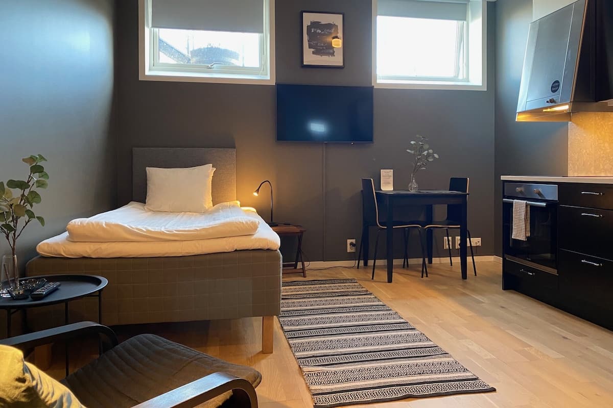Una habitación de hotel pequeña con cama, escritorio y kitchenette.