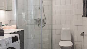 Ein modernes Badezimmer mit einer Glaskabine zur Dusche, einer Toilette und einer Waschmaschine.
