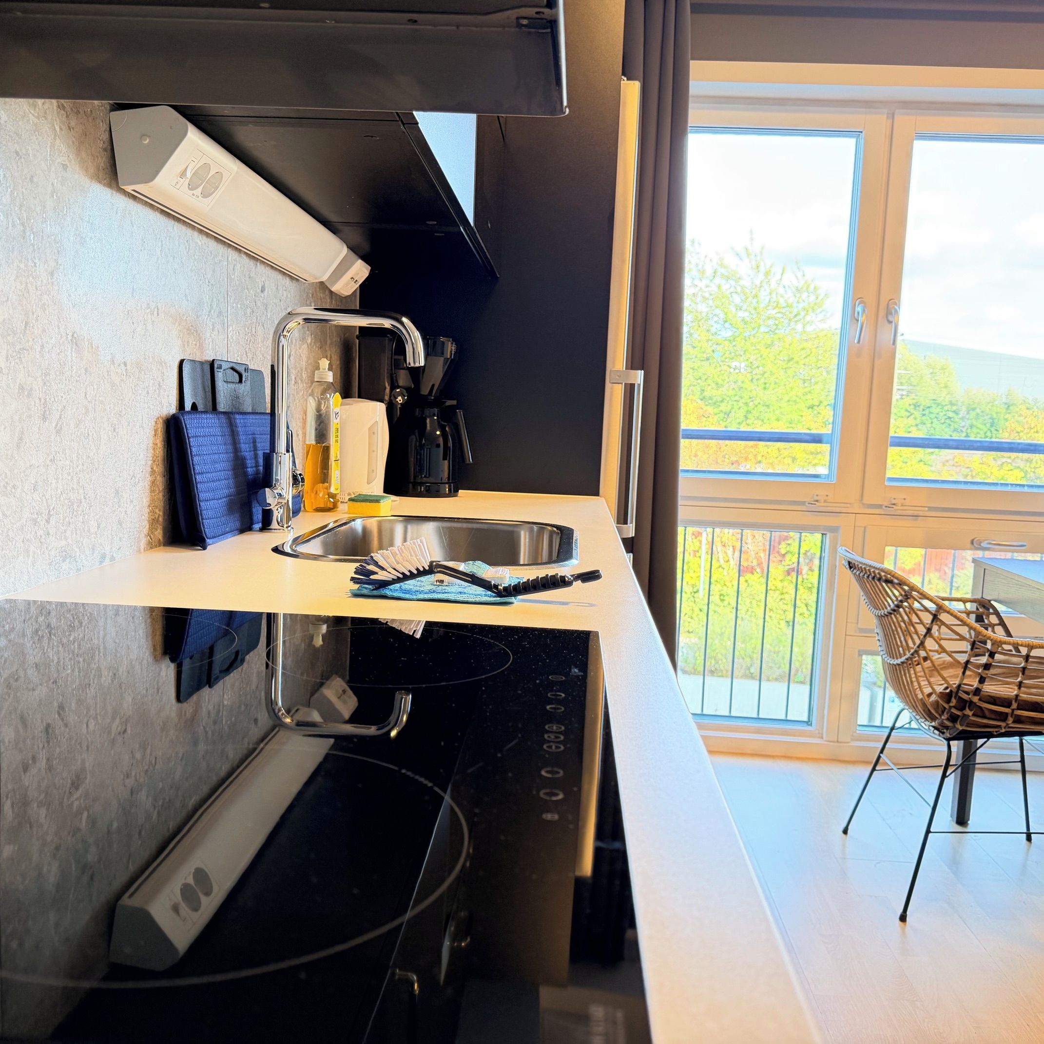 A modern kitchen with a built-in stove, a sink, and a window overlooking a balcony.
