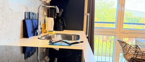 A modern kitchen with a built-in stove, a sink, and a window overlooking a balcony.