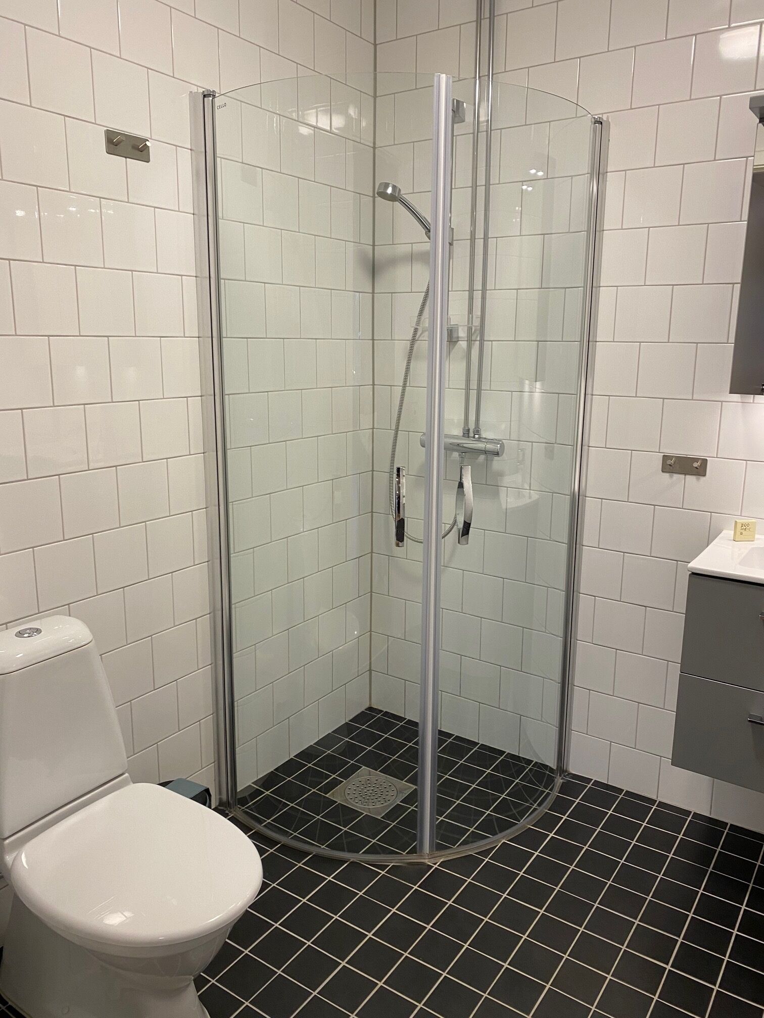 A glass-enclosed shower stall with a handheld showerhead and a wall-mounted faucet.