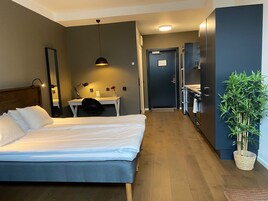 Una habitación de hotel con cama, escritorio, silla y una planta en maceta.