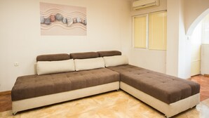 Ein modernes Wohnzimmer mit Ecksofa, einem Bild an der Wand und einer Klimaanlage.