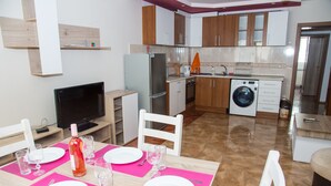 Eine moderne Küche mit Essbereich für vier Personen, inklusive Kühlschrank, Waschmaschine und Fernseher.