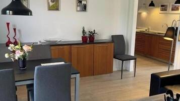 A modern kitchen with wooden cabinets, a dining area with a table and chairs, and a kitchen island with potted plants.