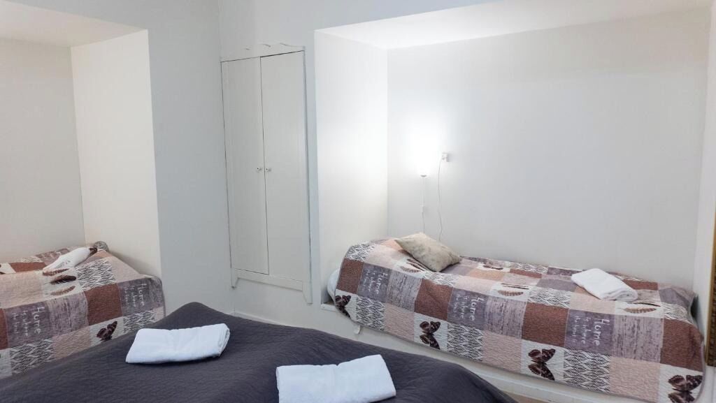 Ett litet, rent rum med två sängar, en garderob och en enkel lampa.