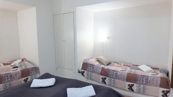 A small, clean room with two beds, a wardrobe, and a single light fixture. - Hilmor's Lejligheder (Viborg)