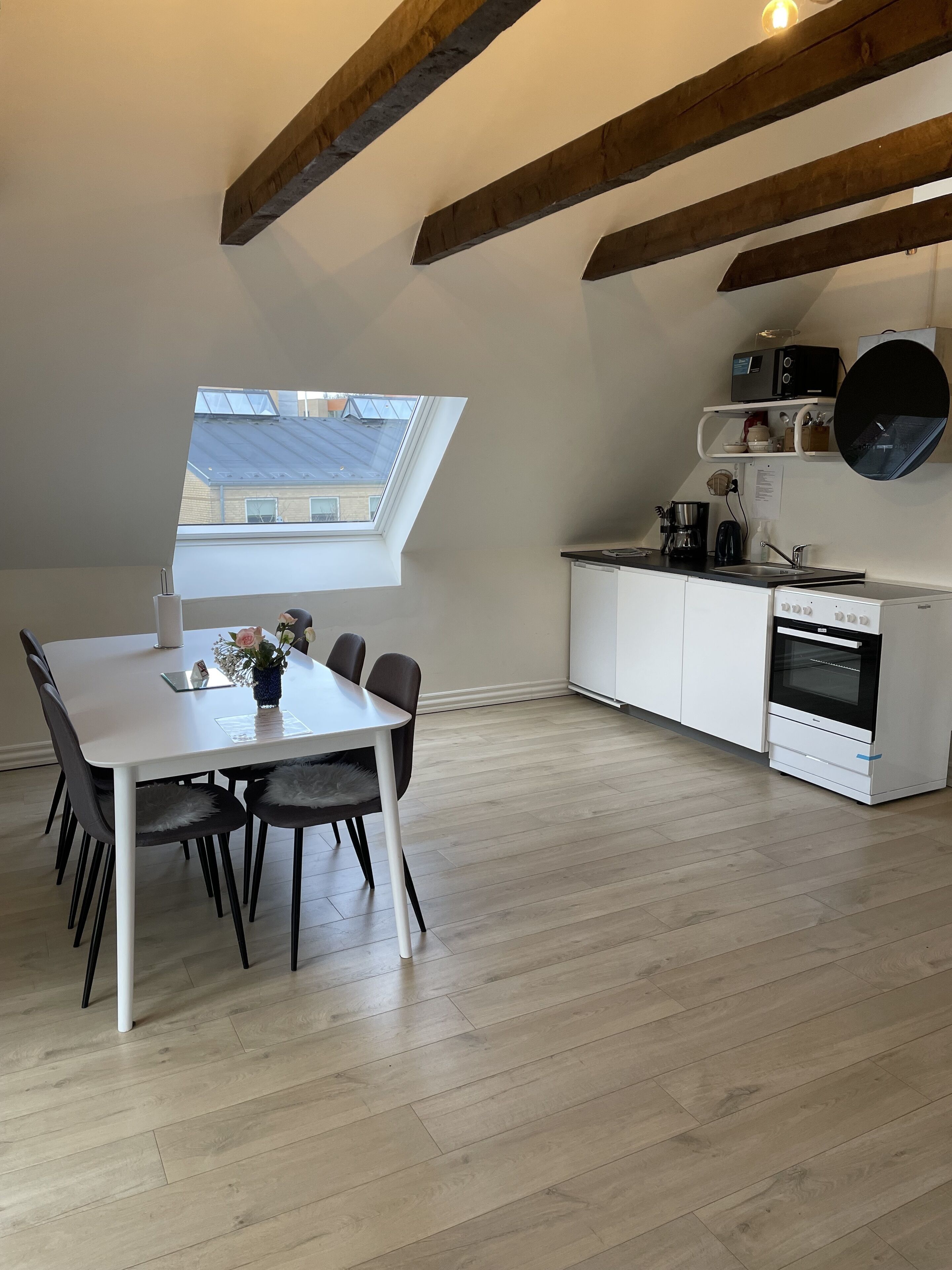 Una cocina moderna con armarios blancos, horno empotrado y ventana sobre el fregadero.