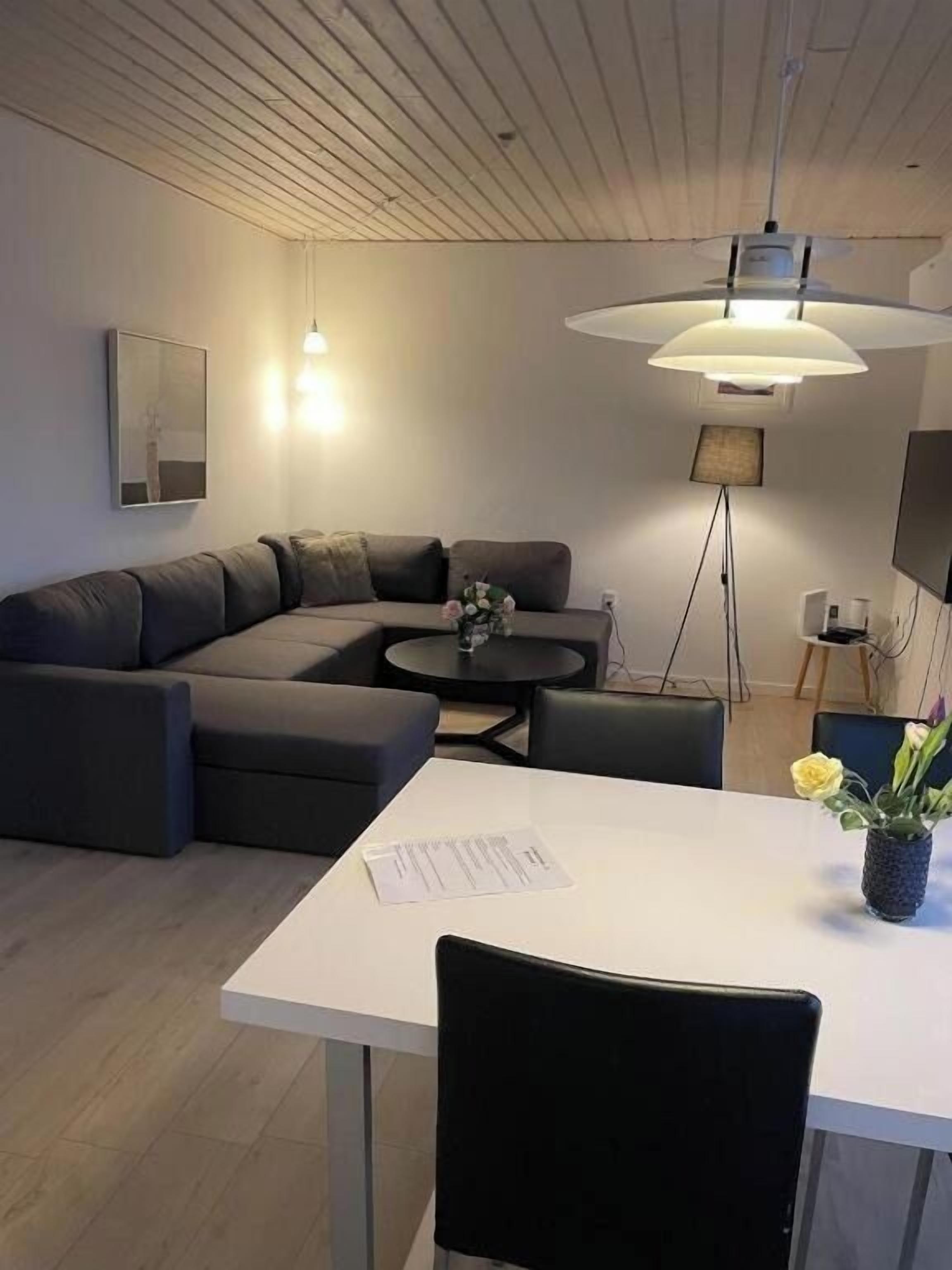 Una sala moderna con un sofá modular, una mesa de comedor y una lámpara colgante.