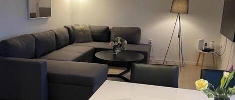 Una sala moderna con un sofá modular, una mesa de comedor y una lámpara colgante.