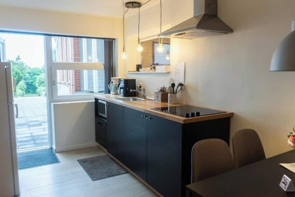 A compact kitchen with a refrigerator, a sink, and a dining area with a table and chairs.