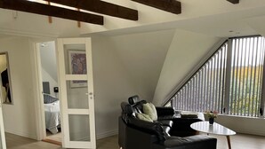 Un loft moderne comprenant un coin repas, un canapé en cuir noir et une vue sur un champ, grâce à de grandes fenêtres.