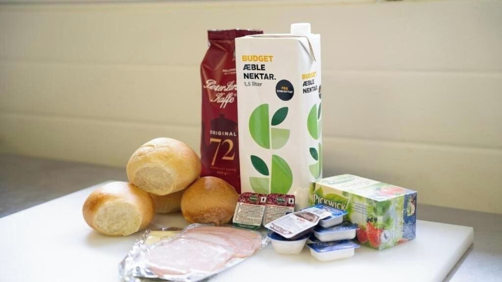 Ein Tisch mit Brot, Milchkarton, Kaffeepackung, Käsepaket und Joghurtbecher.