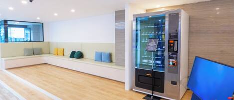 A modern reception area with a seating area, a self-service kiosk, and a large digital screen.