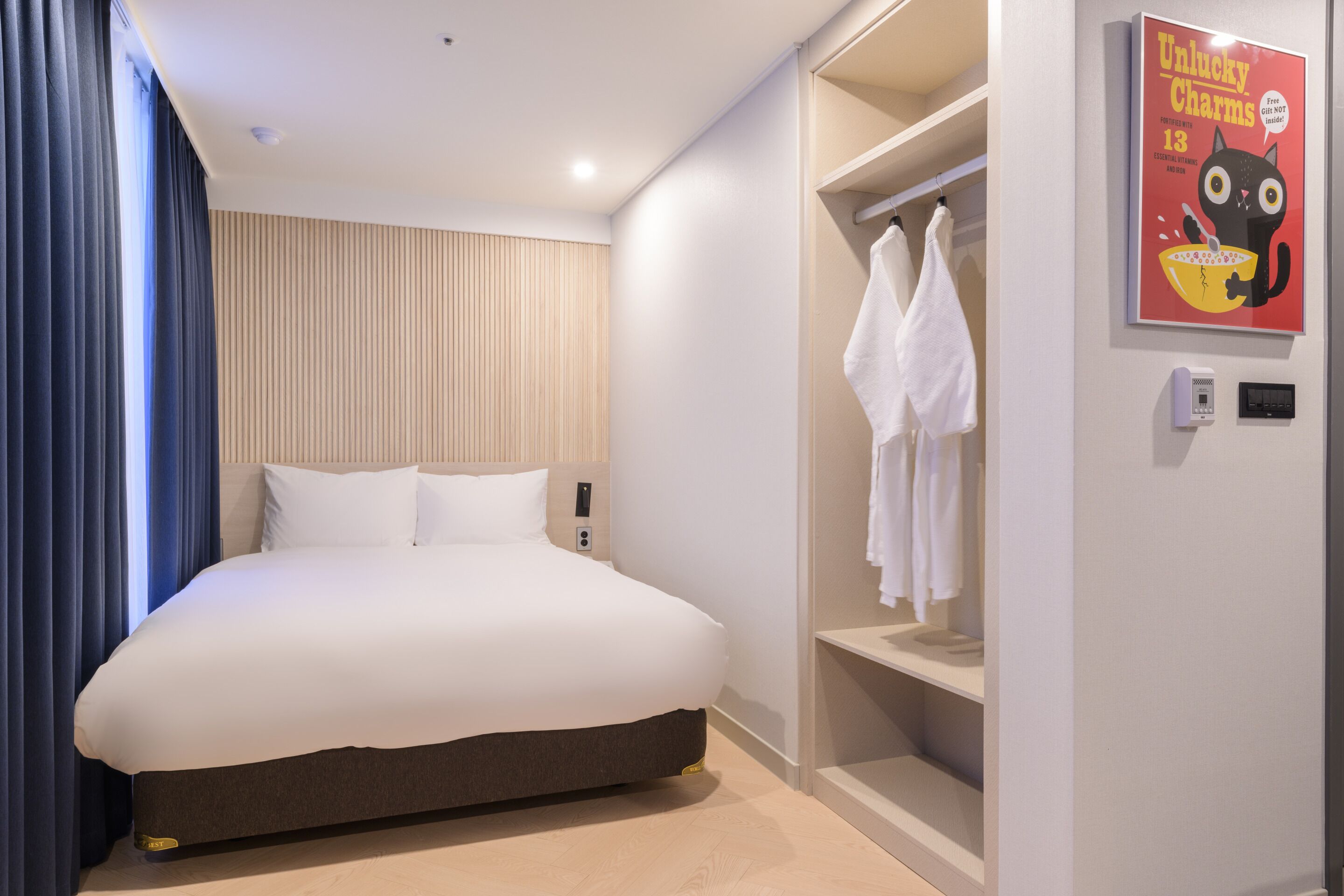 Una habitación de hotel moderna con una cama grande, un vestidor y un cartel en la pared.