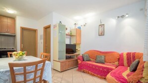 Un espacio habitable compacto con una mesa de comedor, sillas, un sofá, un televisor y una zona de cocina.