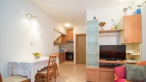 Un espacio habitable compacto con comedor, kitchenette y televisor.