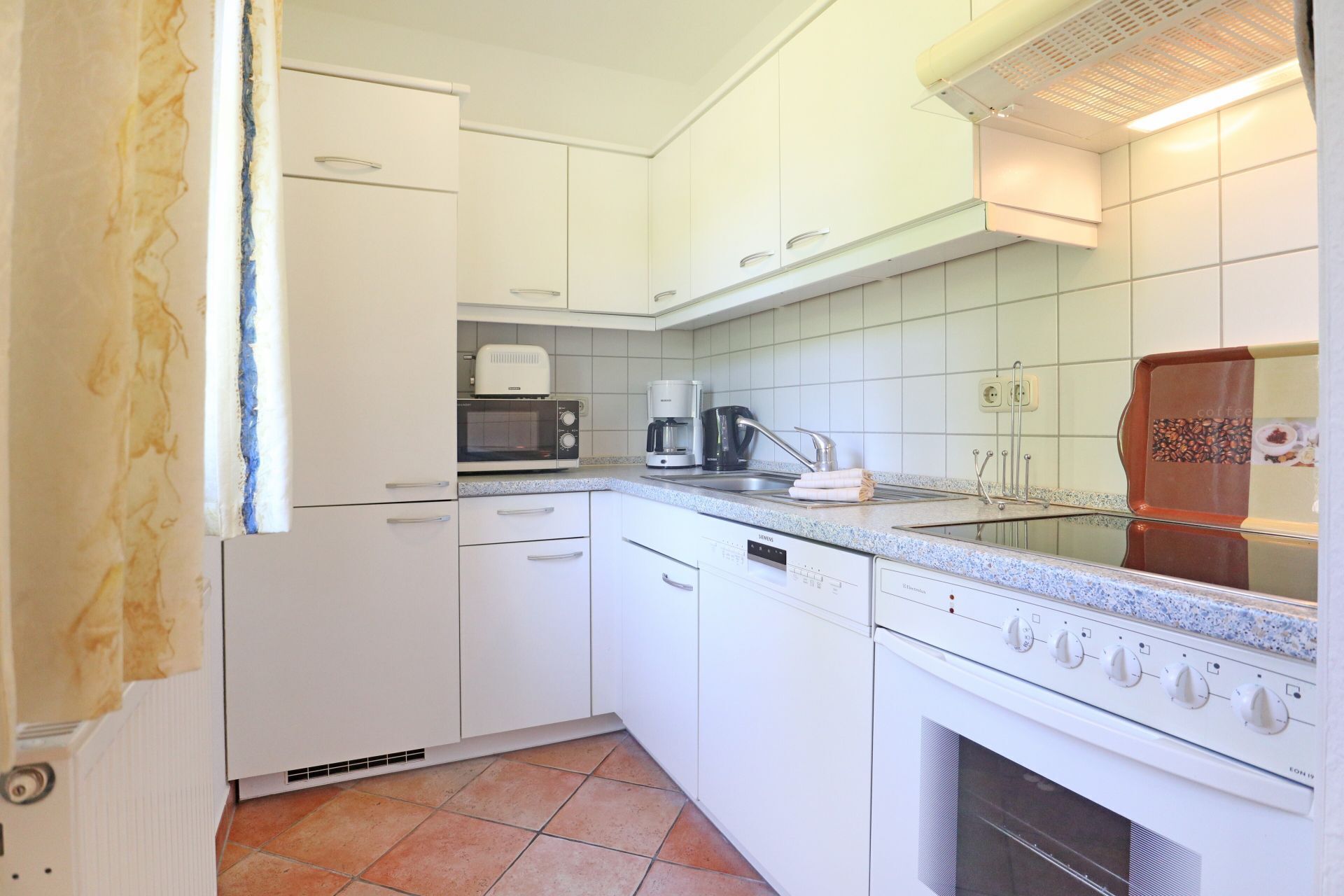 A compact kitchen with white cabinets, a microwave, a coffee maker, and an oven.