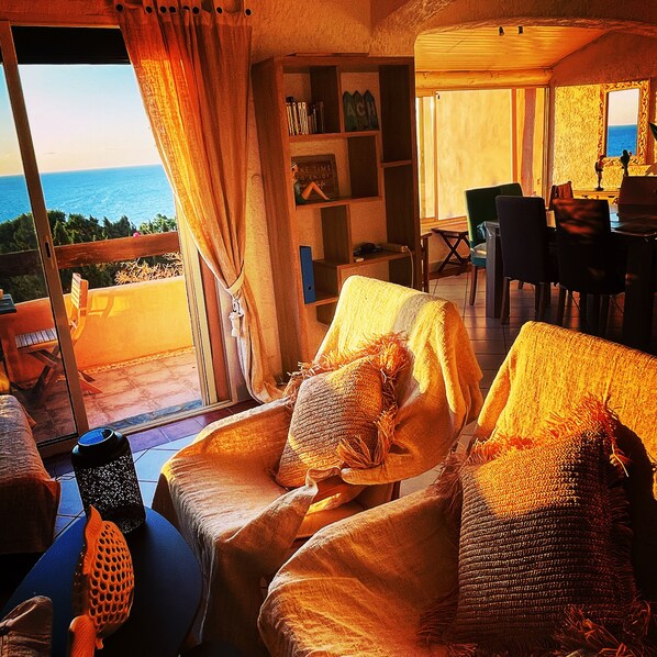A cozy living room with a view of the sea, featuring wicker furniture and a bookshelf. - House in secure residence with exceptional sea view (tarco conca)