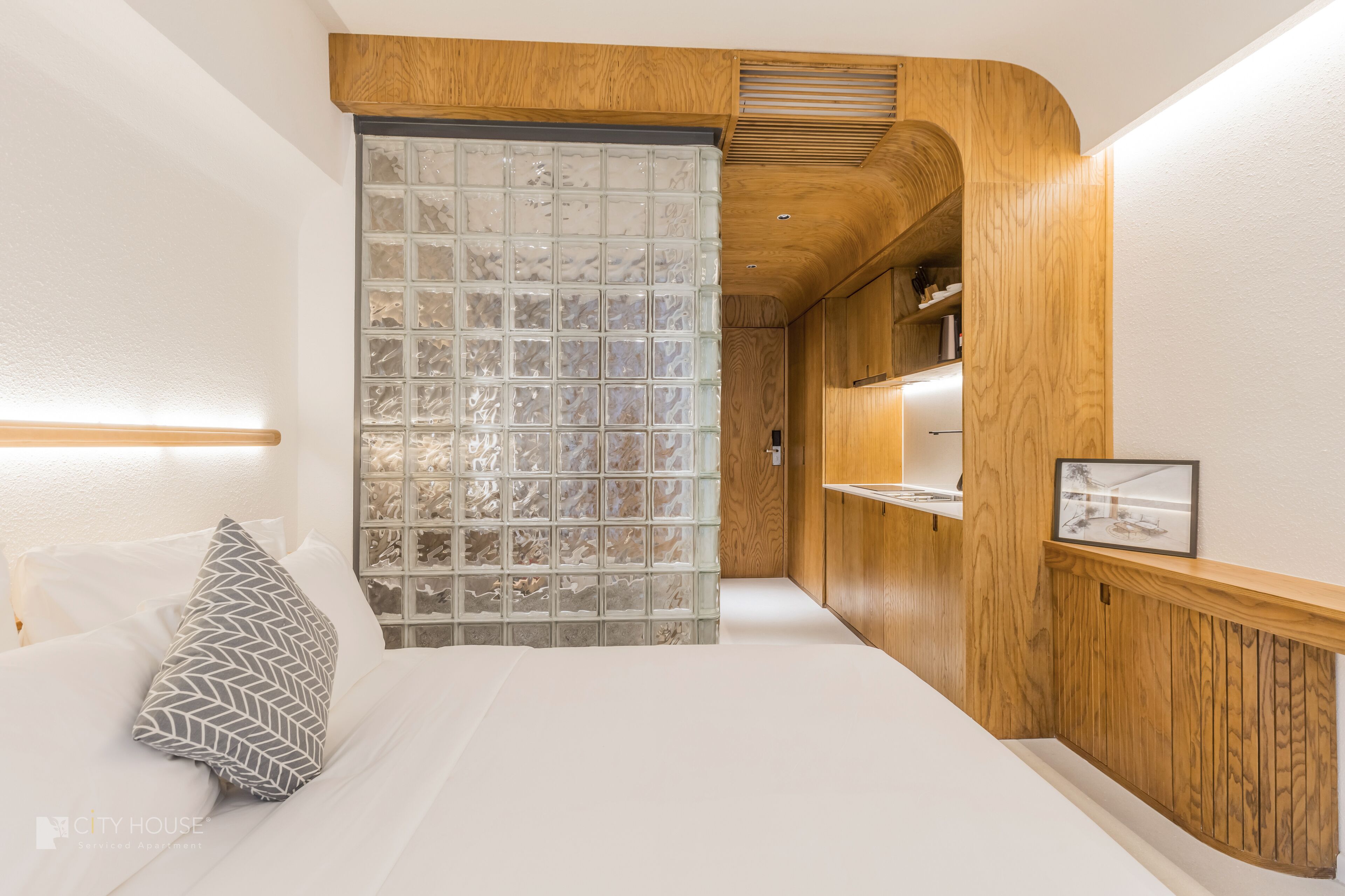 Camera da letto moderna con parete a tema in legno, divisorio in vetro e comodino con una cornice.