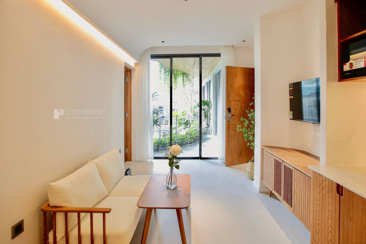 A modern living room with a sofa, a wooden table, and a TV mounted on the wall.
