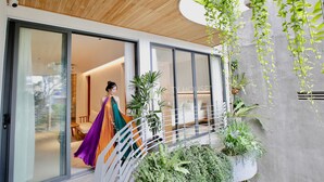 A modern house with a wooden ceiling, large sliding glass doors, and a balcony with plants. - CityHouse VIBE City Oasis (Ho Chi Minh City)