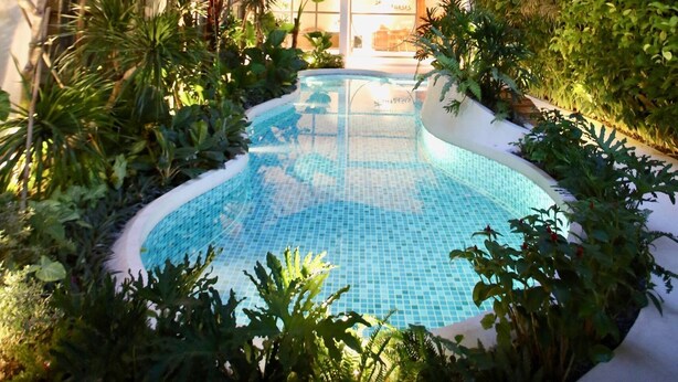 A pool surrounded by lush greenery, with a building in the background. - CityHouse VIBE City Oasis (Ho Chi Minh City)