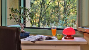 Een bureau met een bonsai, een glas jus d'orange, een boek en een rode lamp.