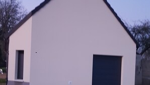 A single-story building with a flat roof, a garage door, and a satellite dish on the roof. - Linen Granne (Petit-Caux)