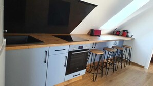 A kitchen with a wooden countertop, a built-in oven, and a high ceiling with a skylight. - Linen Granne (Petit-Caux)