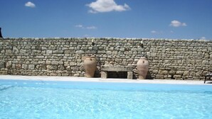 Une piscine avec un mur en pierre et deux grands vases.