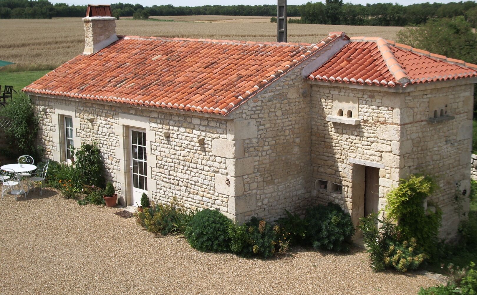 A stone building with a red-tiled roof, a door, and a small window.