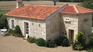A stone building with a red-tiled roof, a door, and a small window.