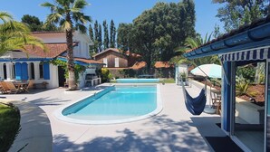 Une piscine avec un espace patio, du mobilier d’extérieur et une vue sur les bâtiments environnants.