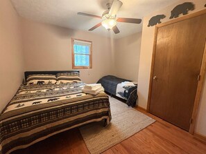 A bedroom with a bed, a window, a door, and a ceiling fan.