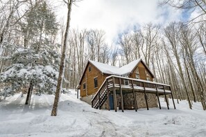 Una baita con facciata in legno, un portico e un paesaggio innevato.