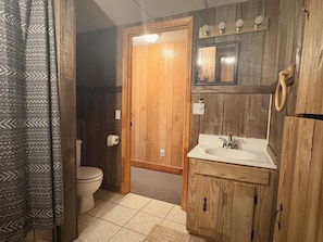 Un bagno con una porta in legno, un water, un lavandino e uno specchio.