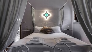 Quarto com cama de dossel, mesa de cabeceira e luminária fixada na parede.