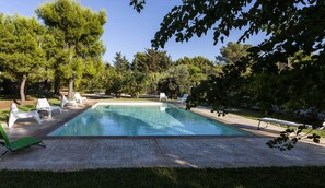 Een seizoensgebonden buitenzwembad en ligstoelen