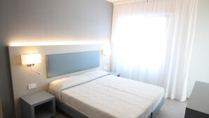 Ein modernes Hotelzimmer mit Bett, Nachttisch und Beistelltisch.