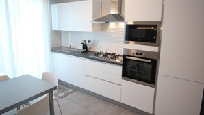 Eine moderne Küche mit weißen Schränken, einem Gasherd, einem Backofen und einer Mikrowelle.